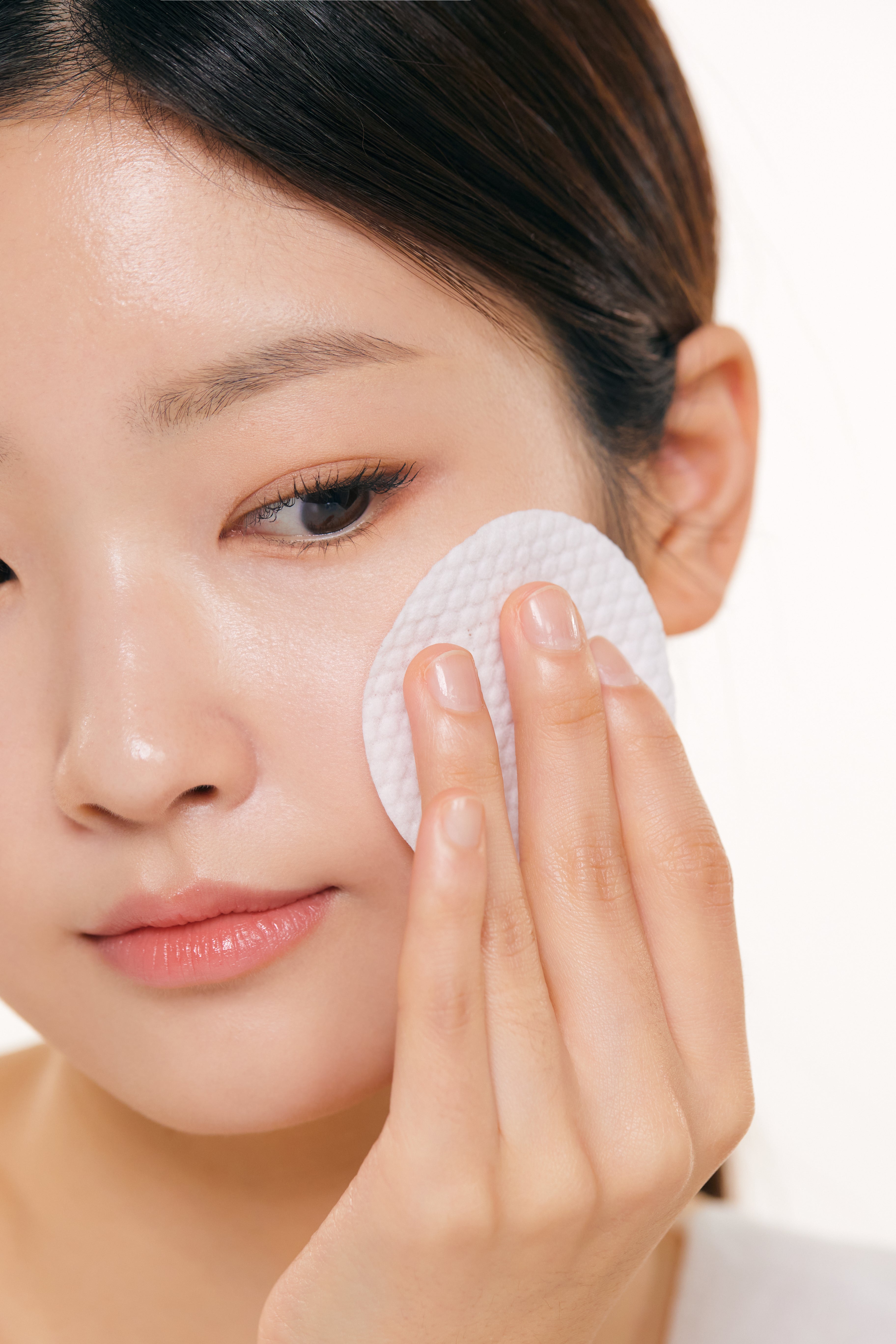 Woman using cotton pad with Korean skincare for acne and redness care
